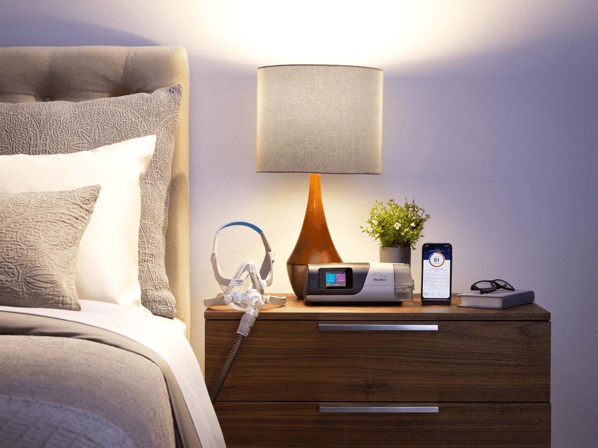 CPAP machine with breathing mask beside a bed for sleep apnea therapy